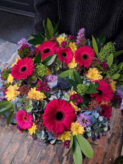 Colourful Wreath - A glorious display of colours in this funeral tribute. Bright and vibrant flowers in a classic arrangement.